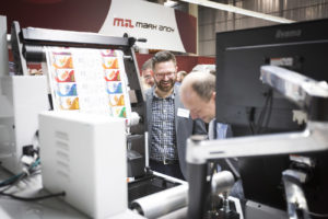 Man smiling while looking down at a Mark Andy printer