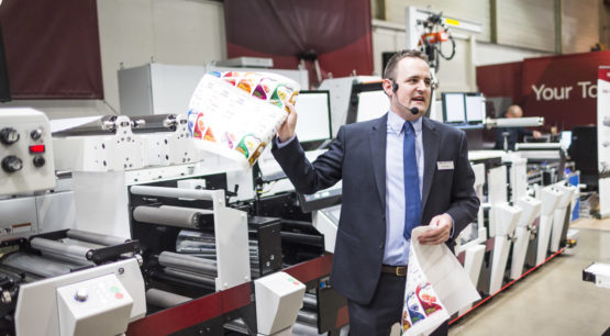 A man demonstrating a product printed on a Mark Andy printer.